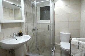 Une salle de bain avec une douche à parois de verre, un lavabo blanc et des toilettes.
