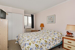 A hotel room with a bed, a television, a window with blinds, a lamp, a picture on the wall, and a dresser. - DAILY ACTIVITIES & LINENS INCLUDED!!! AMAZING BAY & CITY VIEWS!! OUTDOOR POOL! Cozy 1 BR, Right on the Bay! (Ocean City)