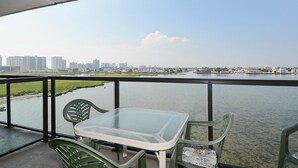 Un balcon avec une table et des chaises donnant sur un plan d’eau et offrant une vue sur la ville.
