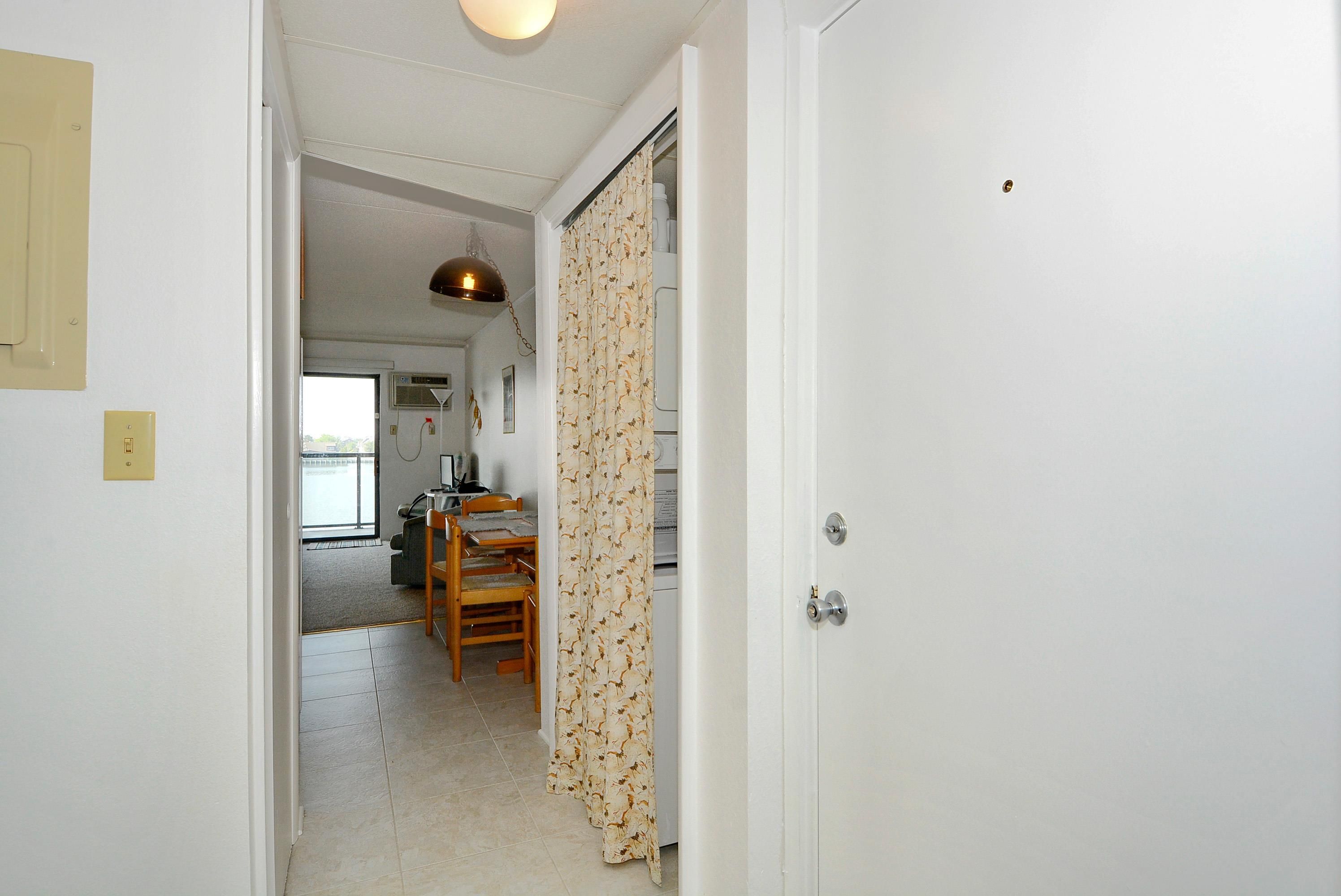 A hallway leading to a room with a door, a ceiling light, and a chair.