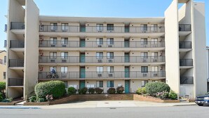 Un immeuble d’appartements à plusieurs étages, doté de balcons, avec un vélo garé au rez-de-chaussée et un ciel dégagé.