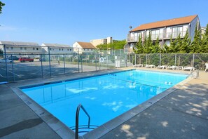 A rectangular swimming pool with a metal ladder, surrounded by a chain-link fence.