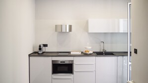 Una cucina moderna con mobili bianchi, forno integrato, cappa aspirante in acciaio inossidabile e un lavello a due vasche.