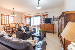 A living room with a sofa, coffee table, TV, and wooden cabinets. - Breathtaking Atlantic View Villa in Guia de Isora with Private Pool an (Guía de Isora)