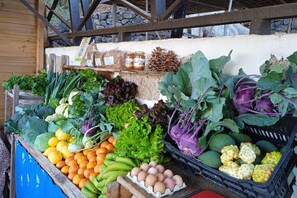 A variety of fresh produce including vegetables, fruits, and eggs displayed at a market stall.