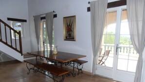A dining area with a wooden table and benches, a staircase, and a view through a glass door. - AIR-CONDITIONED VILLA WITH HEATED POOL AND BREATHTAKING VIEW (Draguignan)