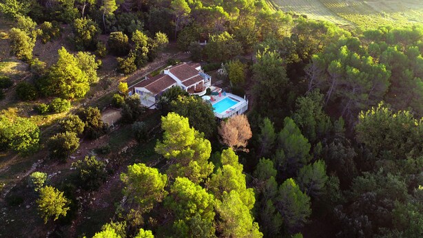 An aerial view of a house surrounded by dense forest, with a visible swimming pool and a large patio area. - AIR-CONDITIONED VILLA WITH HEATED POOL AND BREATHTAKING VIEW (Draguignan)