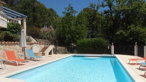 A rectangular swimming pool with clear blue water, surrounded by stone tiles and a stone wall. There are lounge chairs and a pergola with a roof. - AIR-CONDITIONED VILLA WITH HEATED POOL AND BREATHTAKING VIEW (Draguignan)