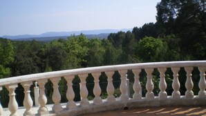 A curved balcony with a balustrade overlooking a forested landscape with distant mountains. - AIR-CONDITIONED VILLA WITH HEATED POOL AND BREATHTAKING VIEW (Draguignan)