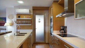A modern kitchen with a large island, stainless steel appliances, wooden cabinets, and a microwave. - FANTASTIC BEACH FRONT APARTMENT IN SALOU 068 BAHIA (Salou)
