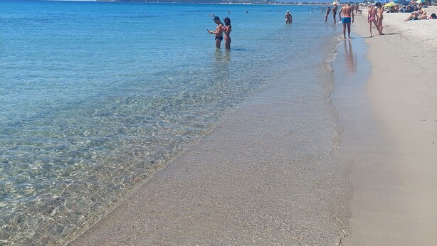 A beach with clear water, people walking, and umbrellas. - Domus Dejanas 180sqm apartment in the center of Quartu Sant'Elena (Quartu Sant'Elena)