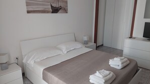 A neatly arranged bedroom with a bed, bedside table, lamp, and a painting on the wall. - Domus Dejanas 180sqm apartment in the center of Quartu Sant'Elena (Quartu Sant'Elena)