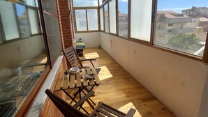 A balcony with wooden furniture and large windows offering a view of the cityscape. - Domus Dejanas 180sqm apartment in the center of Quartu Sant'Elena (Quartu Sant'Elena)