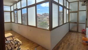 A room with large windows, wooden flooring, and a view of buildings outside. - Domus Dejanas 180sqm apartment in the center of Quartu Sant'Elena (Quartu Sant'Elena)