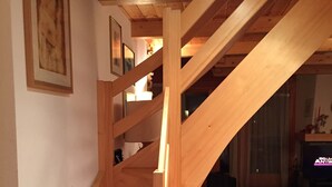 Una escalera de madera en una habitación con alfombras estampadas en el suelo.