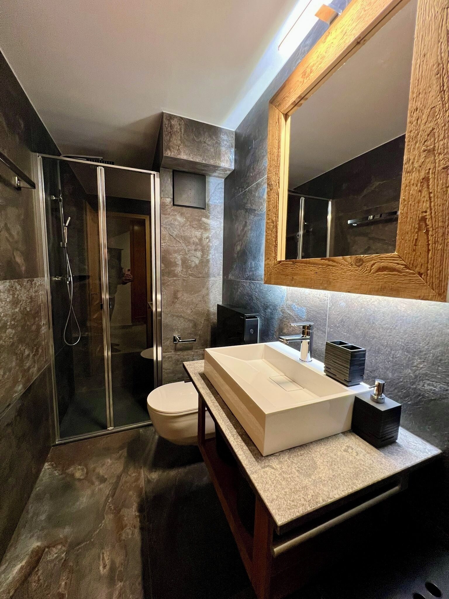 Une salle de bain moderne avec une douche à parois de verre, un lavabo blanc et un grand miroir.