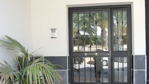 En flisetagbelagt indgang med en dør markeret "31c", en potteplante og en lille ventilationsrist på væggen.