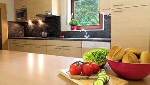 A modern kitchen with a marble countertop, a sink, a microwave, and a window with a view of greenery. - Vulkaneifel Type L-C6 (Gerolstein)