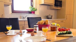 A breakfast setup with eggs, toast, and fruit on a wooden table in a kitchen with wooden cabinets and a window. - Vulkaneifel Type L-C6 (Gerolstein)