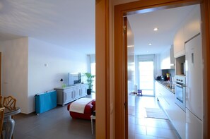 A modern kitchen with white cabinets, a red sofa, and a dining area with a table and chairs.