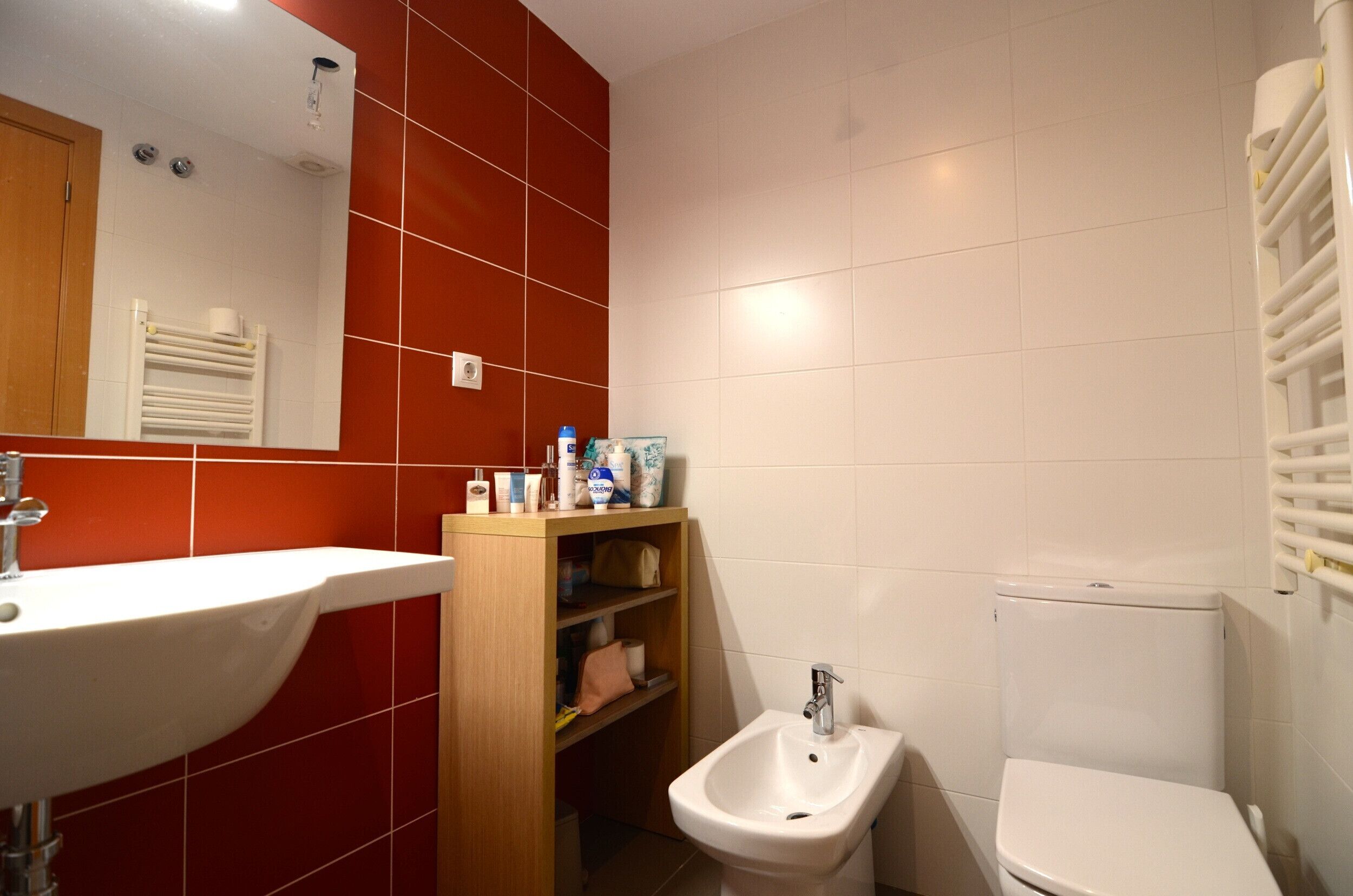 A bathroom with a sink, bidet, toilet, and a mirror.