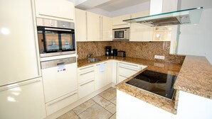 Een moderne keuken met witte kasten, een granieten aanrechtblad, een inbouwoven, een magnetron en een glazen afzuigkap.