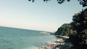 A beach with people, umbrellas, and a rocky shoreline.