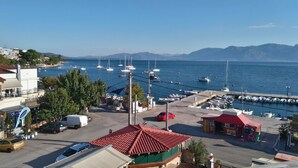 A coastal marina with boats, a parking area, and buildings with red-tiled roofs.