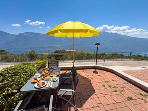 A table set with breakfast, a yellow umbrella, and a scenic mountain view.