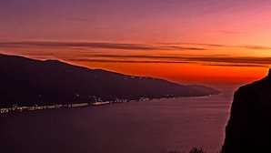 A coastal landscape at sunset with a view of a river and distant city lights. - La Quiete 23 Holideal Apartment Lake View (Tremosine)