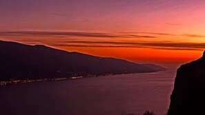A coastal landscape at sunset with a view of a river and distant city lights. - La Quiete 23 Holideal Apartment Lake View (Tremosine)