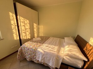 A bedroom with a bed, a wardrobe, and a window casting shadows.