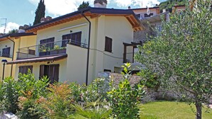 A two-story house with balconies, surrounded by a garden with various plants and flowers. - La Quiete 23 Holideal Apartment Lake View (Tremosine)