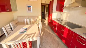 A modern kitchen with red cabinets, a dining area with a white table and chairs, and a red pendant light. - La Quiete 23 Holideal Apartment Lake View (Tremosine)