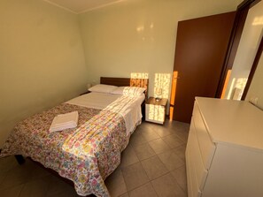 A hotel room with a bed, a bedside table, and a wardrobe.