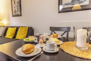 A dining table set with plates of food, including bread, eggs, and cheese, and a candle in a glass holder. - House "dyke Rose" Quiet location, Wi-Fi, 300 meters to the beach, top is directing (Harlesiel)