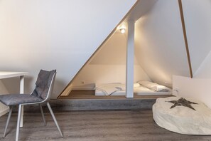 Une pièce avec un plafond en pente, un lit, une chaise et un coussin en forme d’étoile.