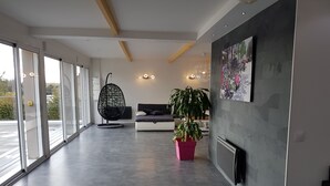 Un interior moderno con un sofá, una silla colgante y una planta en maceta.