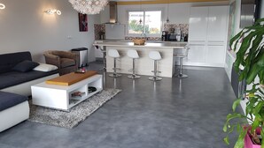 Una sala moderna con sofá, mesa de centro y una zona de cocina con taburete de bar.