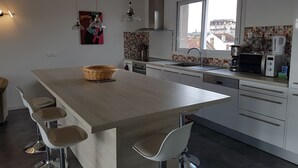 Una cocina moderna con una isla central, taburetes de bar, un microondas y una ventana con vistas a la ciudad.