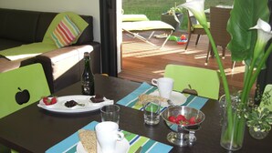 Un coin repas avec une table mise pour le petit-déjeuner, comprenant une bouteille, des fraises, une part de gâteau et un bol de fraises.