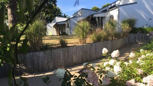 Un quartier résidentiel avec une clôture en bois, une maison blanche et un jardin agrémenté d’hortensias.