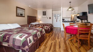 Ein Schlafzimmer mit zwei Betten, einer kleinen Küchenzeile und einer Essecke mit Tisch und Stühlen.