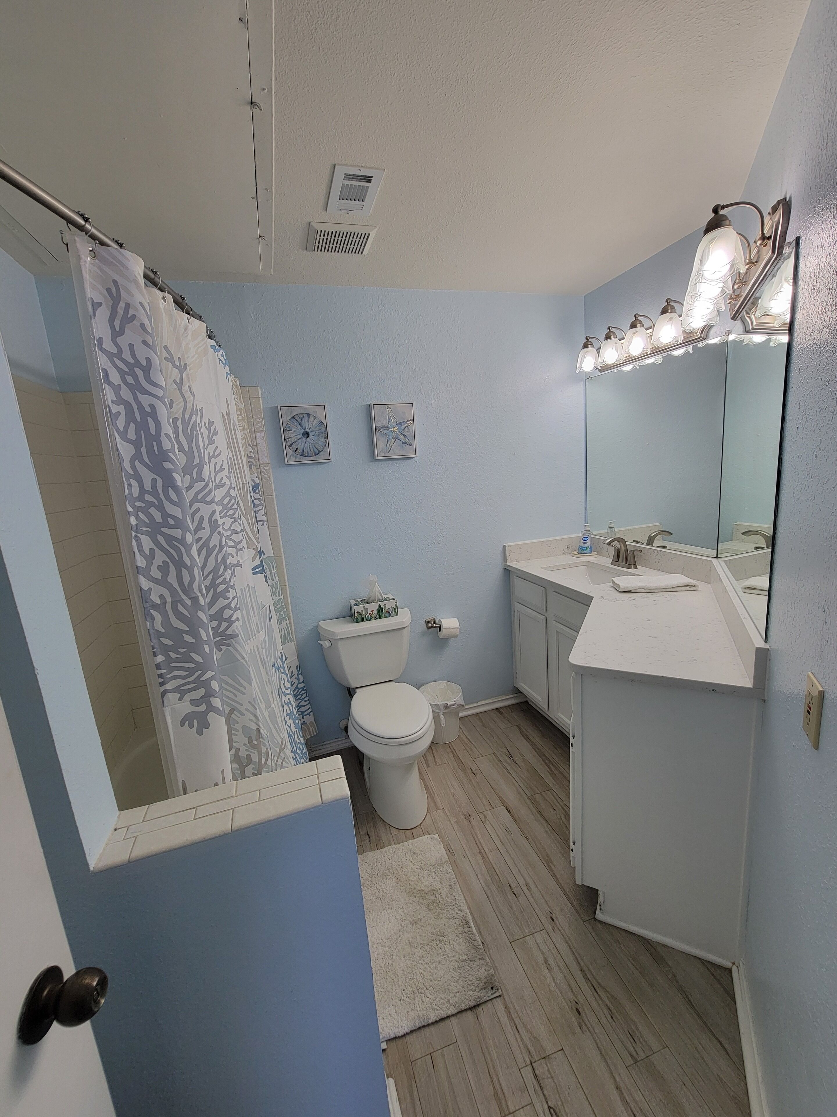 Un baño con inodoro, lavamanos y cortina de ducha.
