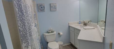 Un baño con inodoro, lavamanos y cortina de ducha.