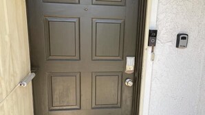 A dark brown door with a keypad lock, a doorbell, and a doormat with a house symbol. - 2 BD Townhome Old Town Scottsdale (Scottsdale)