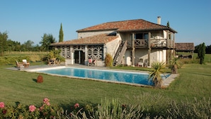 Una casa con piscina, un patio cubierto y una escalera que lleva al piso superior.