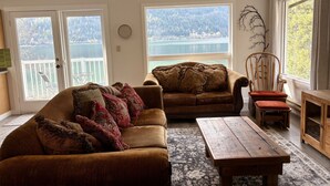 A living room with two sofas, a coffee table, a chair, and a view of a lake through large windows. - Eagle View, Paradise! 2 Beds, Hot Tub, Beach (Nelson)