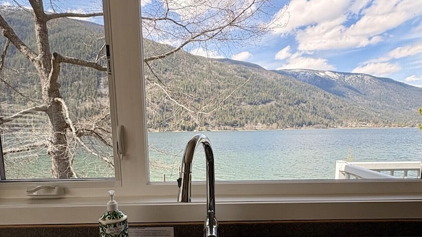 A kitchen with a double stainless steel sink and a window overlooking a lake and mountains. - Eagle View, Paradise! 2 Beds, Hot Tub, Beach (Nelson)