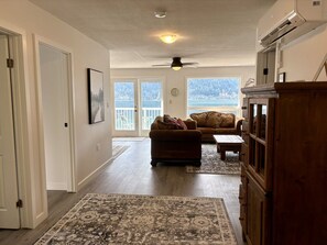 A spacious living area with a large window, a ceiling fan, and a wooden cabinet.